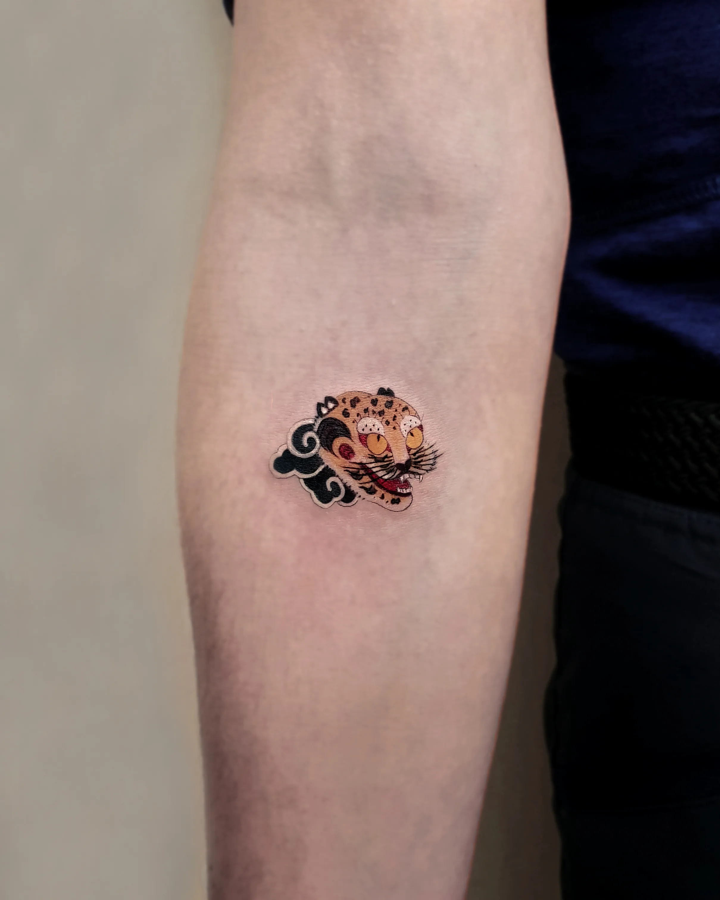 Korean folk-style tiger tattoo by Haesol Choi — small playful minhwa tiger.
